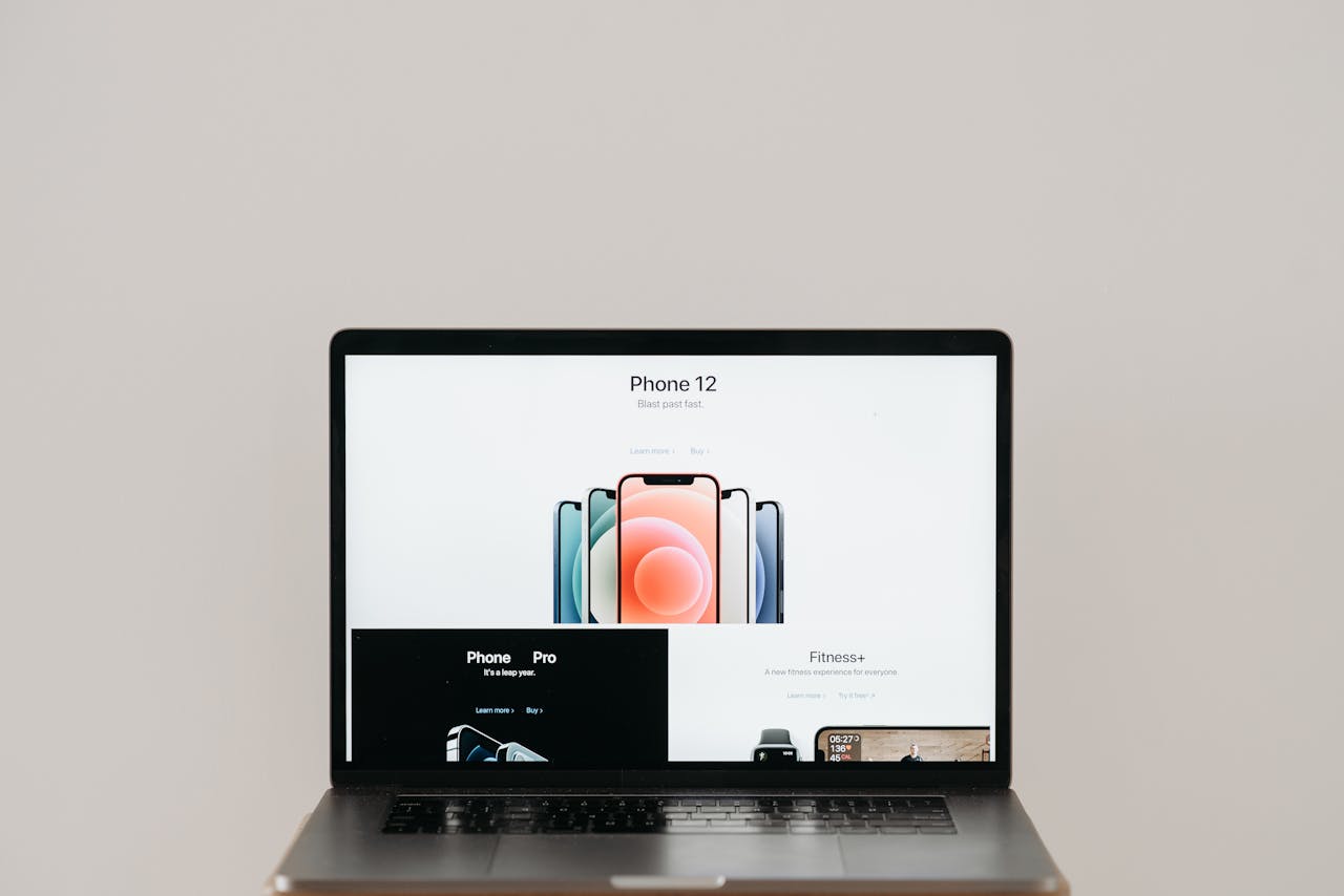 Laptop on stool showing sleek iPhone 12 ad, white background.